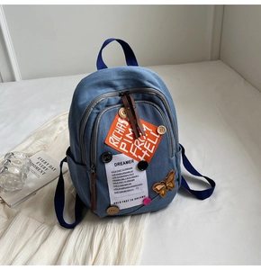 Blue denim backpack detail with orange RICH PIMP patches and colorful button decorations