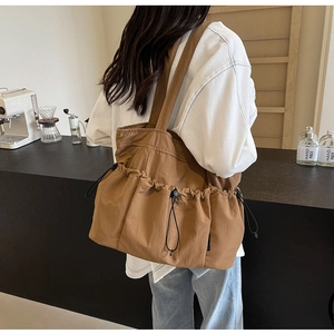 Detail of caramel brown canvas tote bag featuring drawstring pockets and wide strap