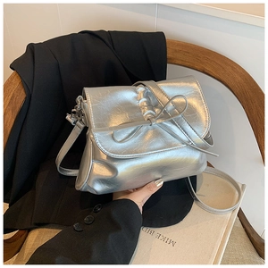 Detail of silver pleated bucket bag with bow ornament and metallic PU leather texture