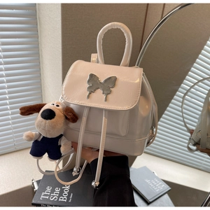 Détail du mini sac à dos blanc verni avec boucle papillon argentée et porte-clés