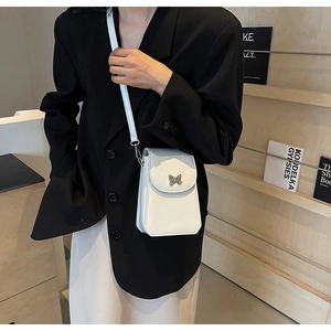 Close-up of white leather crossbody phone bag with silver butterfly clasp detail