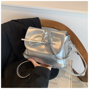 Macro shot of silver metallic pleated handbag featuring a bow detail and lobster clasp strap