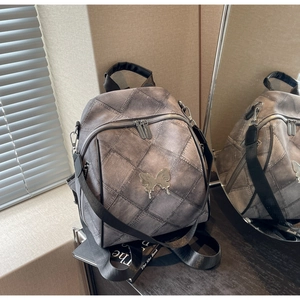 Detail showing grey distressed denim texture and silver butterfly buckle on multi-way backpack