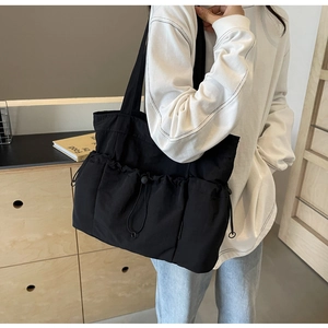 Close-up of black canvas tote bag with functional drawstring and multiple exterior pockets