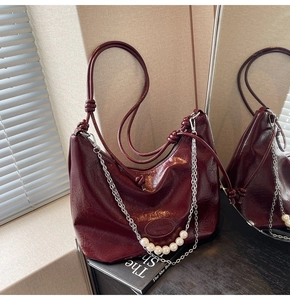 Dettaglio borsa hobo bordeaux in vernice con accenti di perle e catena argentata