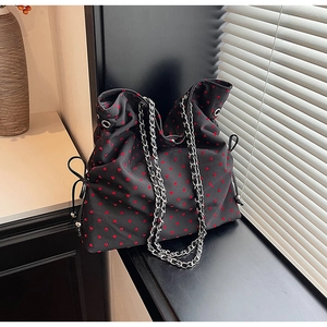 Close-up of black fabric tote bag with red heart patterns and silver metal chain strap