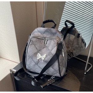 Detail of grey quilted denim backpack featuring a silver butterfly buckle and texture