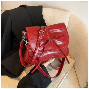 Detail of red pleated leather bucket bag with bow accent and silver metal buckle