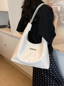 Large white hobo bag with metal hearts and chain strap shown on model's shoulder