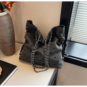 Close-up of gray tote bag with polka dots, bow embroidery and silver metal chain strap