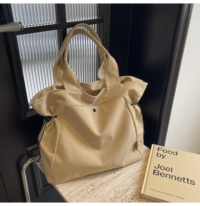 Close-up of cream canvas tote bag with drawstring detail and metal snap button