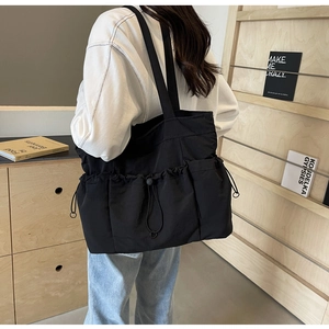 Detail showing functional drawstring pockets and textured surface of the black canvas tote bag