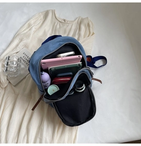 Top view of the spacious blue denim backpack interior showing laptop and daily essentials