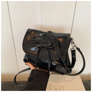 Detail of black pleated bucket bag featuring a decorative bow and silver hardware hooks