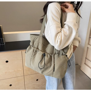 Detail of olive green large canvas tote bag showing the side drawstring design and texture