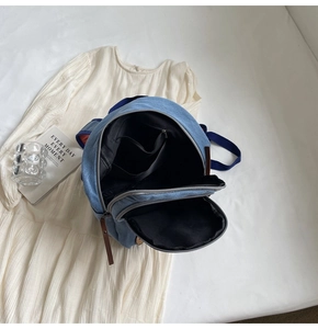 Detailed interior of blue denim backpack showing functional inner pockets and zipper