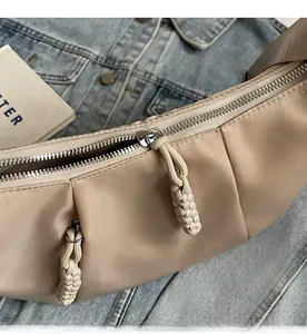 Detail of smooth metal zipper with woven rope puller on a khaki nylon crescent bag