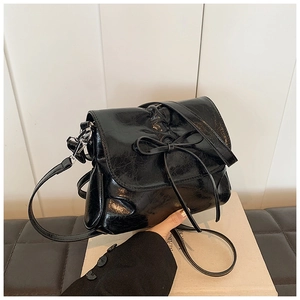 Detail of black oiled leather shoulder bag with chic bow and silver metal hardware hook