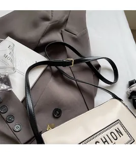 Detail of adjustable black shoulder strap on minimalist cream FASHION letter print bag