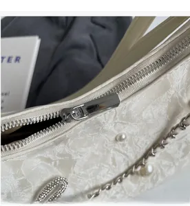 Détail de la fermeture éclair argentée sur un sac cabas blanc plissé avec perles