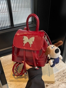 Mini sac à dos mode en cuir verni rouge avec détail papillon argenté et peluche suspendue