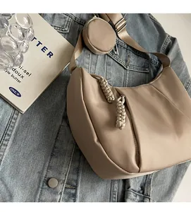 Detail of khaki half-moon crossbody bag with round pouch on denim jacket with books
