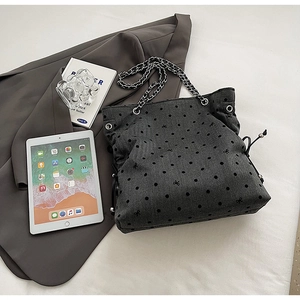 Detail of grey canvas tote bag with black polka dots and metal chain shoulder strap