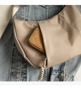 Detailed view of apricot nylon crescent bag with functional exterior zipper pocket