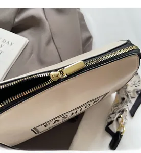 Detailed close-up of cream white leather bag with gold zipper and stylish fashion logo