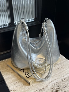 Borsa hobo in pelle verniciata argento con perle e catena su una superficie di marmo