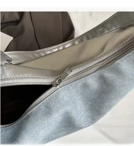 Detail of smooth metal zipper and denim patchwork on this silver crossbody bag