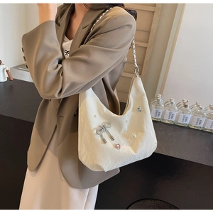 Détails du cabas ivoire avec nœud en strass, perles et accents en forme de cœur