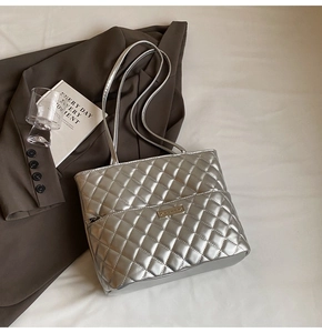 Detailed view of silver quilted tote bag featuring metallic finish and brand plaque