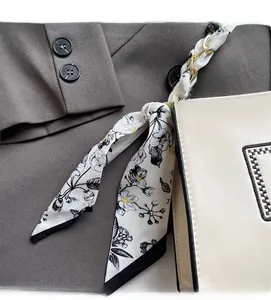 Detail of cream crossbody bag featuring a floral silk scarf accent and embroidery