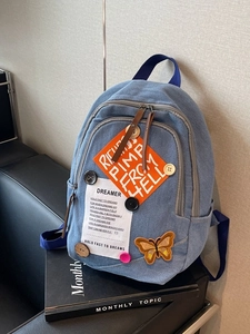 Vintage denim backpack with colorful patches and butterfly embroidery on a leather sofa
