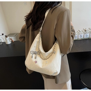 Détail du sac cabas plissé crème avec perles et nœud orné de strass en forme de cœur rose