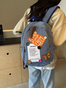 Blue denim backpack featuring retro patches and butterfly embroidery on model