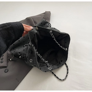 Detail of dark grey polka dot tote bag with silver chain strap and interior pocket