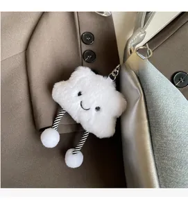Close-up of a white plush cloud keychain with embroidered face on a silver handbag