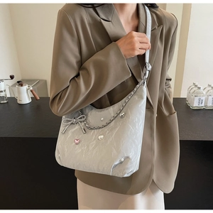 Détail du sac cabas argenté avec perles, breloque coeur rose et un nœud métallique