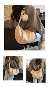 Detail of beige half-moon shoulder bag with woven zipper and round coin purse accessory