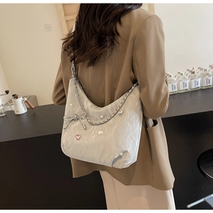 Détail du sac hobo gris avec accents de perles et breloque nœud en cristal