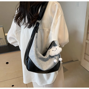 Detail of crescent denim patchwork crossbody bag with plush cloud charm and strap buckle