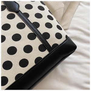 Close-up of polka dot canvas fabric and black pebbled leather texture on tote bag