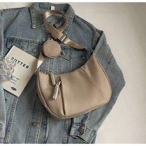Detail of khaki crescent crossbody bag with pleated texture and round coin purse charm
