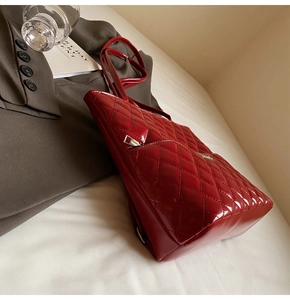 Close-up of red quilted patent leather tote bag with glossy finish and zipper detail