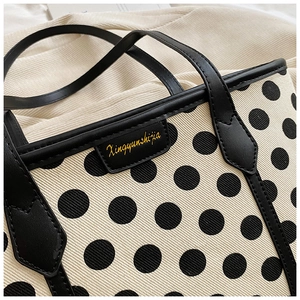 Close-up of the canvas polka dot tote bag showing premium stitching and leather logo label