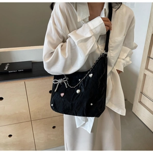 Détail du sac plissé noir avec nœud argenté, perles et breloques en strass en cœur