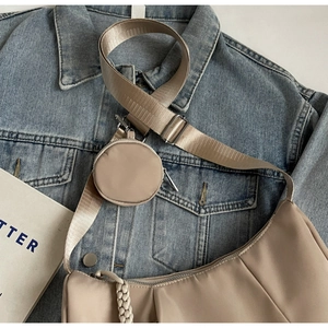 Detail of nylon crescent crossbody bag with adjustable strap and small round pouch