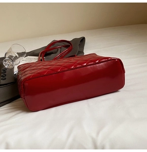 Detail of red quilted patent leather tote bag with glossy finish and slim shoulder straps